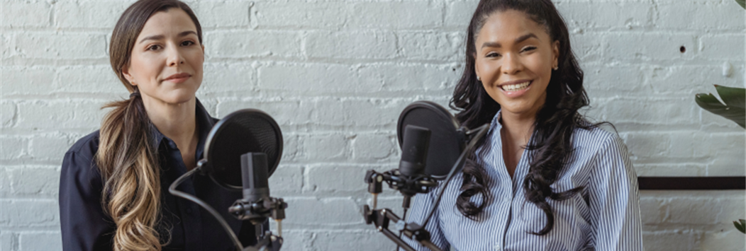 Photo of two women smiling behind microphones